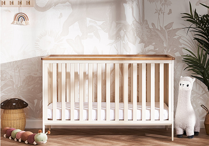 Stylish cot bed with open slatted sides, 3 position base height and a warm cashmere finish with contrasting wooden trim.