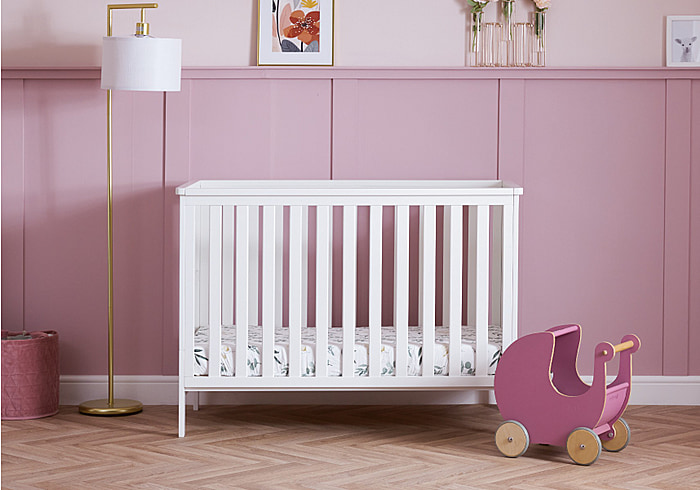 Modern, white mini cot bed with open slatted sides and 3 base heights. Crafted from pine.