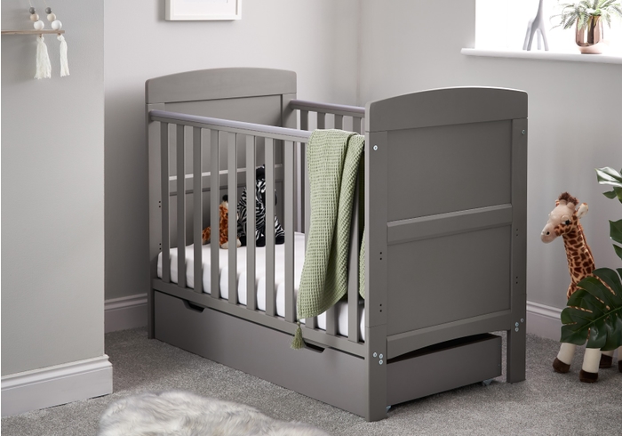Stylish grey wooden cot bed with under drawer, open slatted sides and solid curved end panels. Includes teething rails.