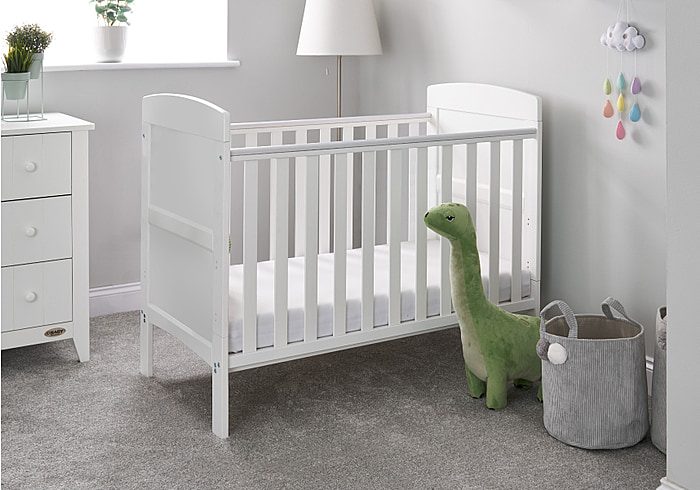 Stylish white wooden cot bed with open slatted sides and solid curved end panels. Includes teething rails.