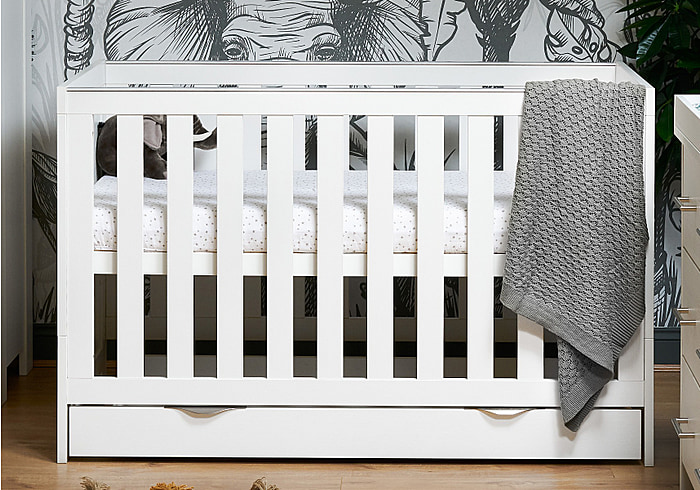 Contemporary white wash cot bed with under drawer. Three mattress base heights and teething rails. Transforms easily to a toddler bed.