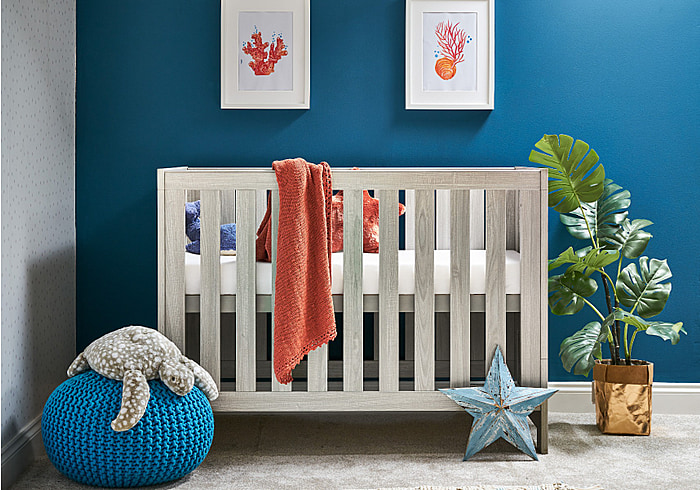 Cot bed with a contemporary grey wash finish. Open  slatted sides, teething rails, 3 base heights.