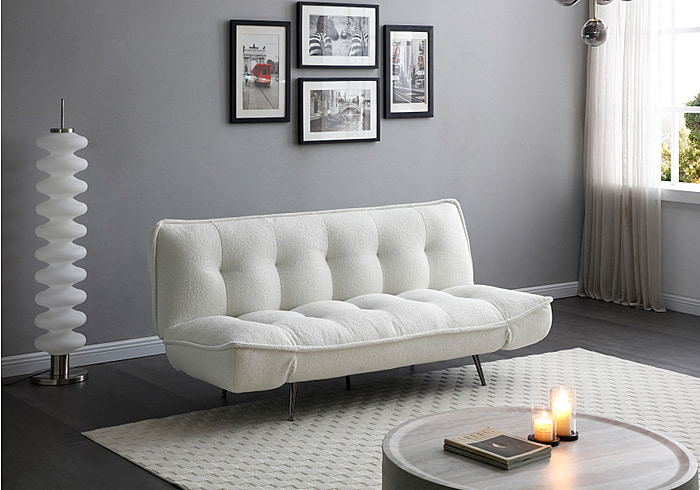 A Contemporary 3 seater sofa bed, upholstered in a soft Ivory sherpa fabric. It stands on stylish splayed chrome feet.