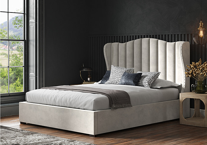 Luxurious velvet upholstered ottoman bed frame, featuring a winged headboard with stud detailing.