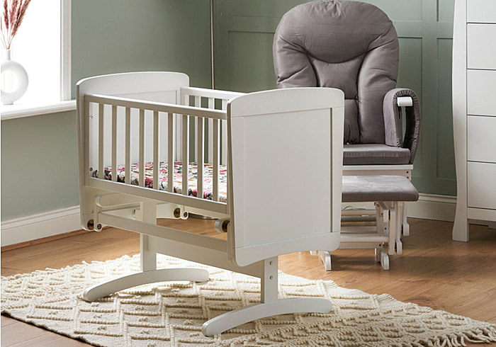 White wooden gliding baby crib with open slatted sides and solid end panels.