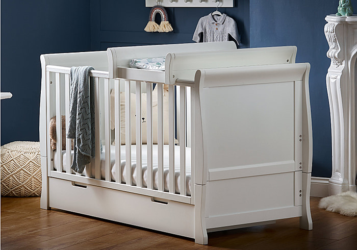 White traditional sleigh design cot bed with under drawer and cot top changer. Open slatted sides, 3 position base height and teething rails.