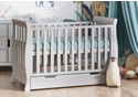 Elegant, sleigh style mini cot bed in a grey finish with under drawer. 3 base heights, teething rails, open slatted sides.