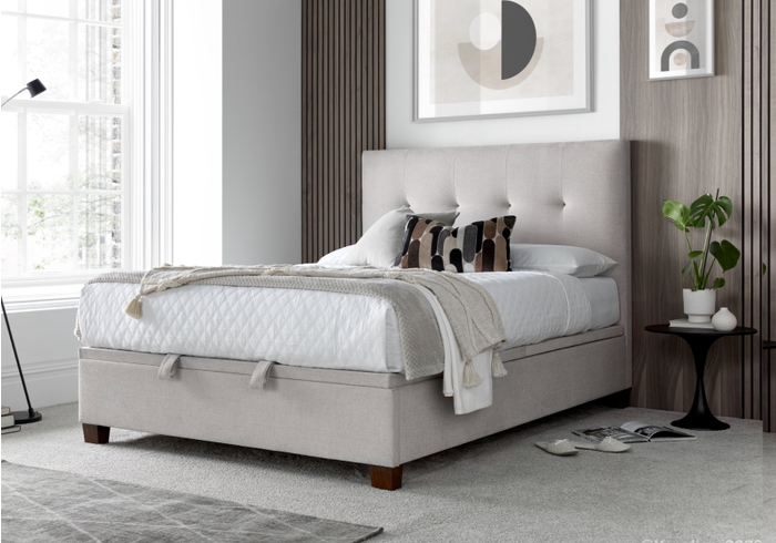 Luxurious pale cream fabric ottoman bed frame with modern dark wooden feet.